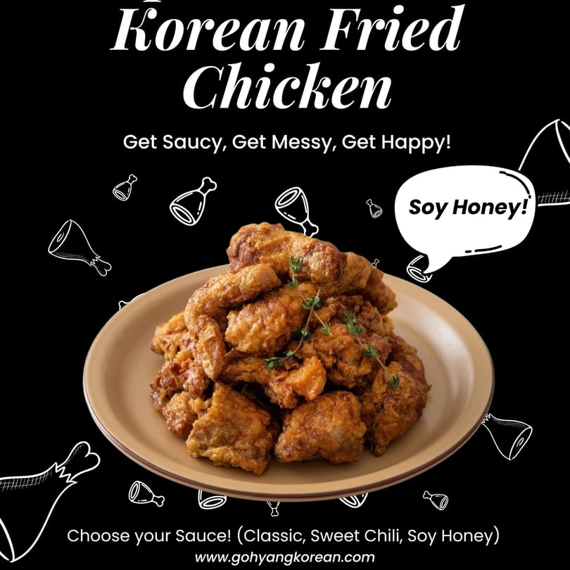 A plate piled high with golden-brown Korean fried chicken, garnished with fresh herbs.