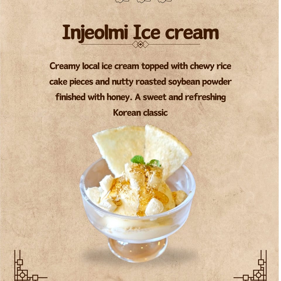 Injeolmi ice cream in a glass bowl, topped with rice cake, soybean powder, honey, and mint.