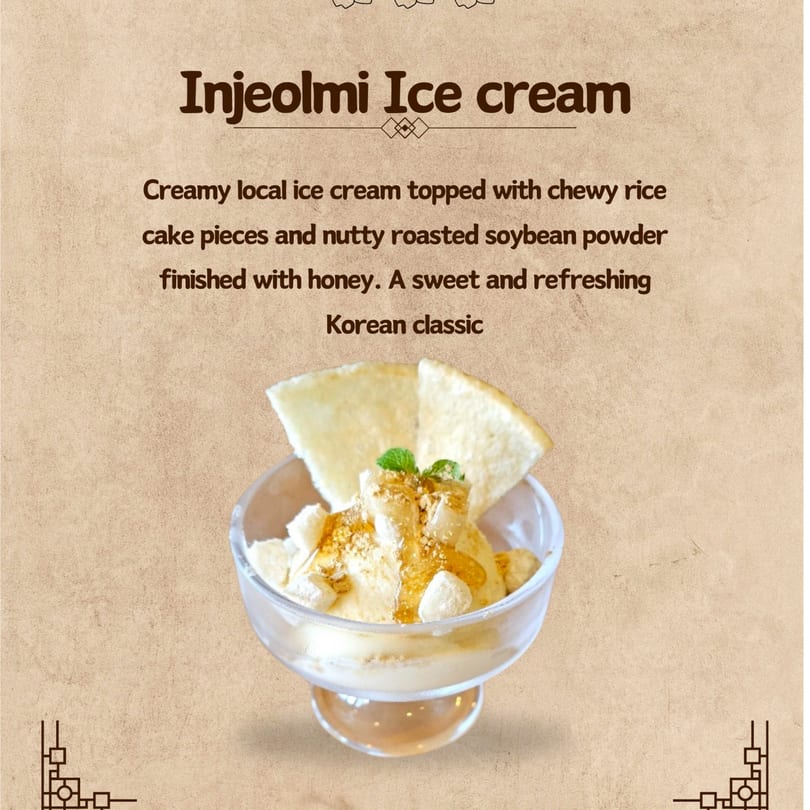 Injeolmi ice cream in a glass bowl, topped with rice cake, soybean powder, honey, and mint.